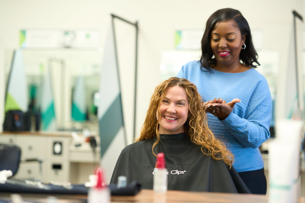 A Great Clips stylist putting hair treatment into a woman’s hair.